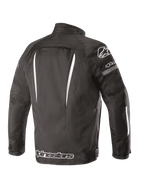 Chaqueta impermeable Alpinestars Gunner V2, vista posterior, negro y blanco, construcción textil con detalles blancos verticales, logotipo grande de Alpinestars en la parte inferior de la espalda y logotipo A-star en el hombro, equipamiento de conducción urbana