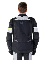Chaqueta Alpinestars Bogotá Pro Drystar®, chaqueta de moto para touring de aventura, negro, gris hielo y amarillo flúor, vista posterior que muestra la marca 'TECH TOURING' en una franja amarilla fluorescente, amplio panel de ventilación en la espalda y correas de cintura ajustables, equipamiento técnico para todas las estaciones