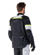 Chaqueta Alpinestars Bogotá Pro Drystar®, chaqueta adventure touring, negro, gris hielo y amarillo flúor, vista posterior con un gran panel de bolsillo trasero, marca 'TECH TOURING', logotipo de Alpinestars y detalles amarillos fluorescentes, equipamiento técnico de tejido textil