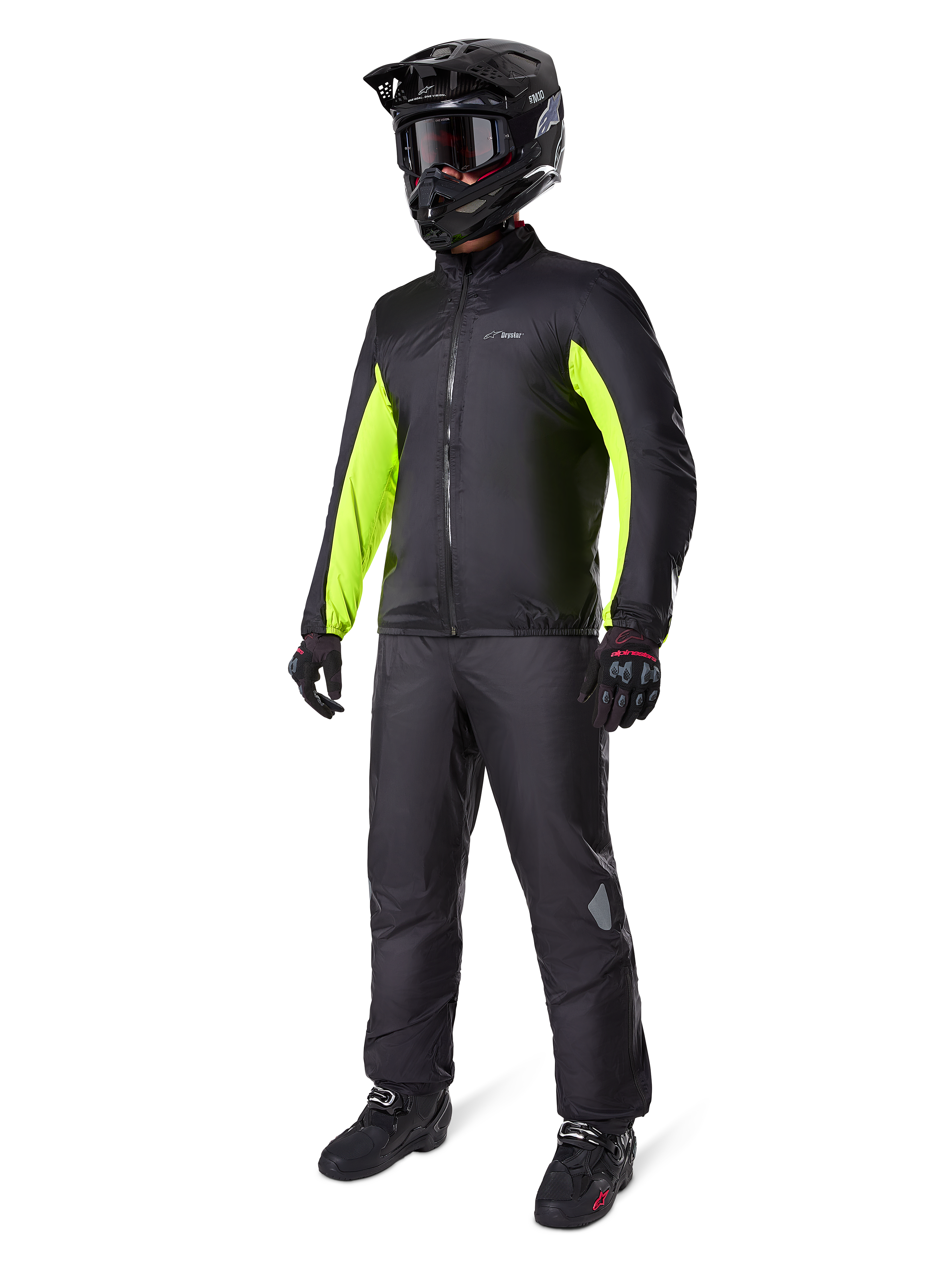 Motociclista vistiendo el forro de la chaqueta Alpinestars Bogotá Pro Drystar®, negro con paneles amarillo flúor brillantes en las mangas, combinado con pantalones negros a juego, casco de motocross y guantes negros, equipamiento de aventura impermeable para todas las estaciones