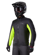 Forro impermeable de la chaqueta Alpinestars Bogotá Pro Drystar®, negro con detalles en amarillo flúor brillante en las mangas, usado por un piloto con casco negro y gafas, equipamiento técnico de motociclismo.