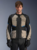 Chaqueta Alpinestars Andes Air Drystar, chaqueta de turismo de aventura, negro, gris laurel y azul brillante, usada por un modelo con guantes negros, con amplios paneles de malla en el pecho para flujo de aire, bolsillos de carga frontales y detalles en azul, equipo de protección para mototurismo