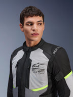 Chaqueta Alpinestars Andes Air Drystar®, chaqueta de touring para moto, gris hielo y gris oscuro con acentos en amarillo neón, usada por un modelo masculino, con paneles de malla 2D para ventilación, logo Alpinestars con coordenadas en el pecho y confección textil resistente
