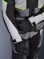 Chaqueta Alpinestars Andes Air Drystar®, chaqueta de moto touring, gris hielo y gris oscuro con detalles en amarillo neón, primer plano que muestra los paneles de malla y las correas de ajuste, usada con guantes negros Alpinestars