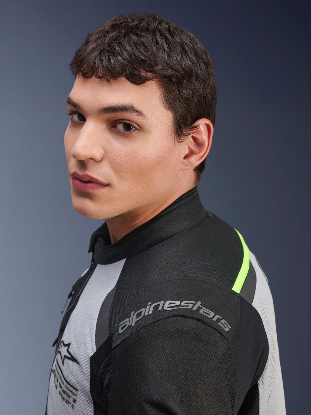 Primer plano de un modelo con la chaqueta Alpinestars Andes Air Drystar® en gris hielo, gris oscuro y negro, con detalles en amarillo neón y paneles de malla, y el logotipo de Alpinestars visible en el hombro.