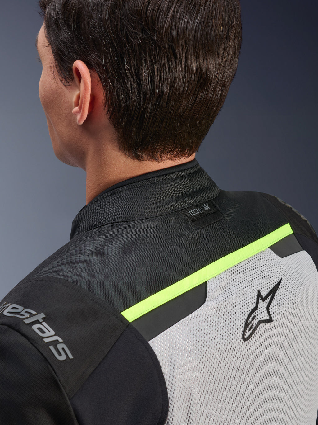Chaqueta Alpinestars Andes Air Drystar®, chaqueta textil para moto, gris hielo, gris oscuro y negro, detalle de la vista posterior de la parte superior de la espalda y el hombro, con paneles de malla transpirable, acentos en amarillo fluorescente y el logo Tech-Air en el cuello.