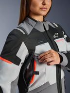 Alpinestars Stella Andes V4 Drystar®, chaqueta de moto touring para mujer, gris y coral, impermeable, con detalle de ajuste de ventilación en el pecho.