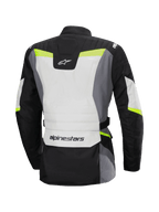 Chaqueta impermeable Alpinestars Stella ST-1, vista trasera, chaqueta de moto de turismo para mujer, gris hielo, negro y amarillo flúor, presenta el logotipo de Alpinestars en la parte inferior de la espalda y en la parte superior del cuello, diseño de turismo de aventura con construcción textil protectora y detalles fluorescentes.