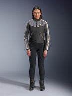 Woman wearing Alpinestars Stella T-Dyno WR Jacket, Black Dark Gray and Ecru, front view, textile motorcycle jacket with vintage-inspired design, featuring chest and sleeve branding, worn with black pants and boots