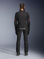 Chaqueta Alpinestars Stella ST-2 Air, chaqueta de moto para mujer, negra, vista trasera con logo rojo en la parte superior de la espalda y marca gris en la parte inferior, combinada con pantalones y botas de moto negros a juego, diseño touring moderno con paneles de malla y detalles reflectantes