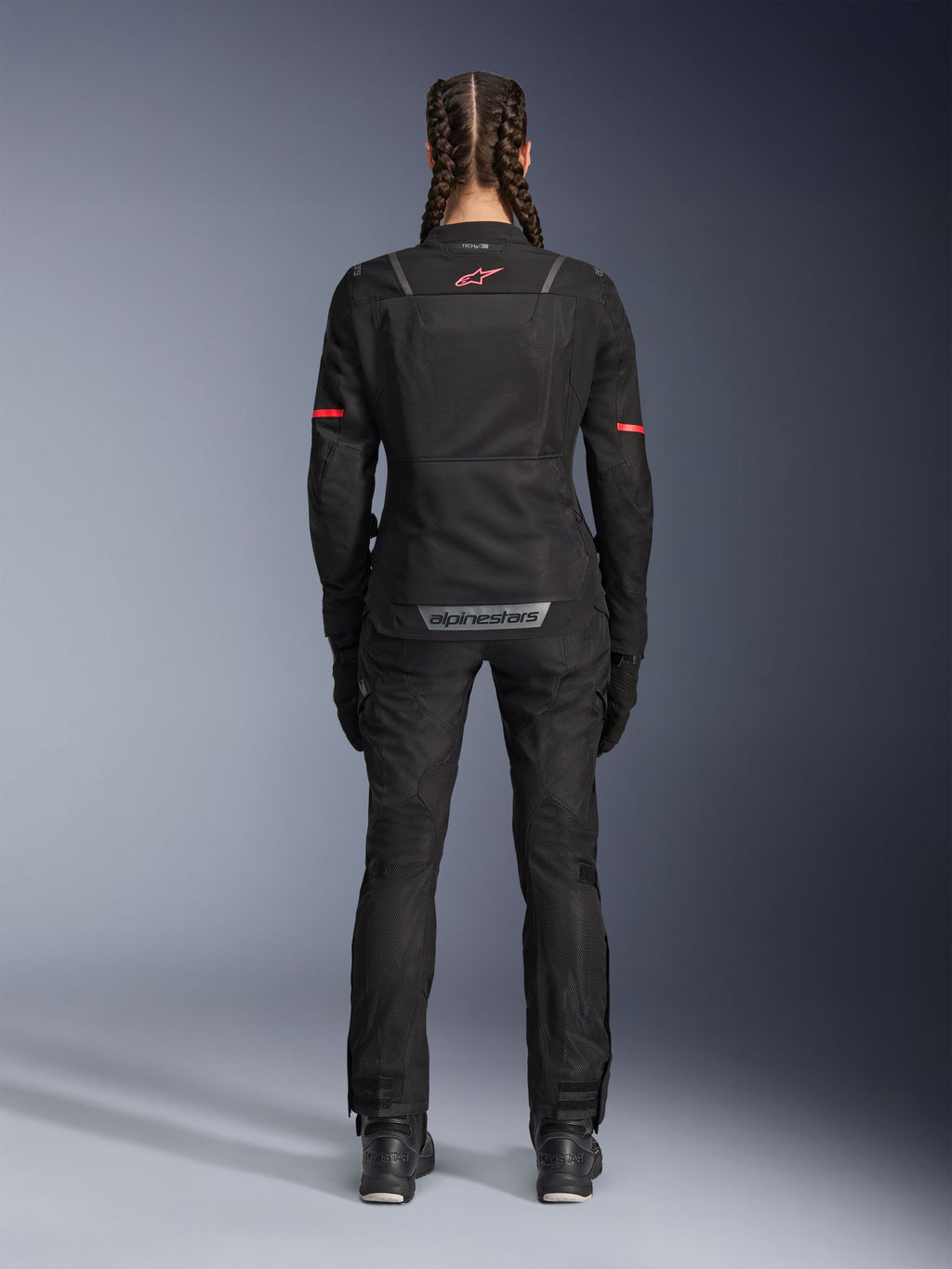 Alpinestars Stella Andes Air Drystar® Pants, pantalones de moto para mujer, negros, vista trasera, usados con una chaqueta de malla a juego con detalles rojos, resaltando los paneles de ventilación de malla y la marca reflectante en la parte inferior de la espalda, diseñados para aventura y turismo de carretera.