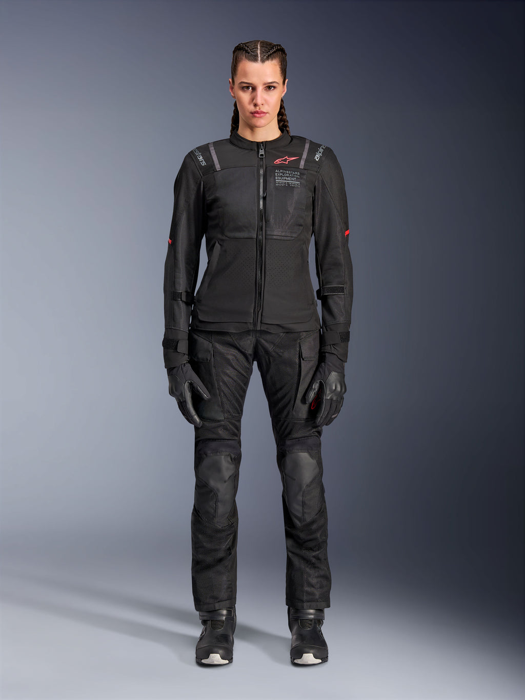 Chaqueta Alpinestars Stella ST-2 Air, negra, vista de estudio de cuerpo completo de una motociclista con pantalones y guantes de moto negros a juego, con paneles de malla de alto flujo, detalles del logotipo en rojo y un diseño touring moderno