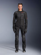 Chaqueta Alpinestars Stella ST-2 Air, negra, vista de estudio de cuerpo completo de una motociclista con pantalones y guantes de moto negros a juego, con paneles de malla de alto flujo, detalles del logotipo en rojo y un diseño touring moderno