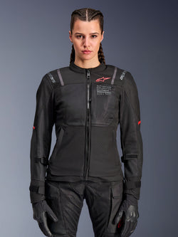 Alpinestars Woman Stella ST-2 Air Jacket, Women's Motorcycle Jacket, Black, front view on model, featuring mesh panels, red logo on chest, and Alpinestars Exploration Equipment branding, worn with black gloves and riding pants