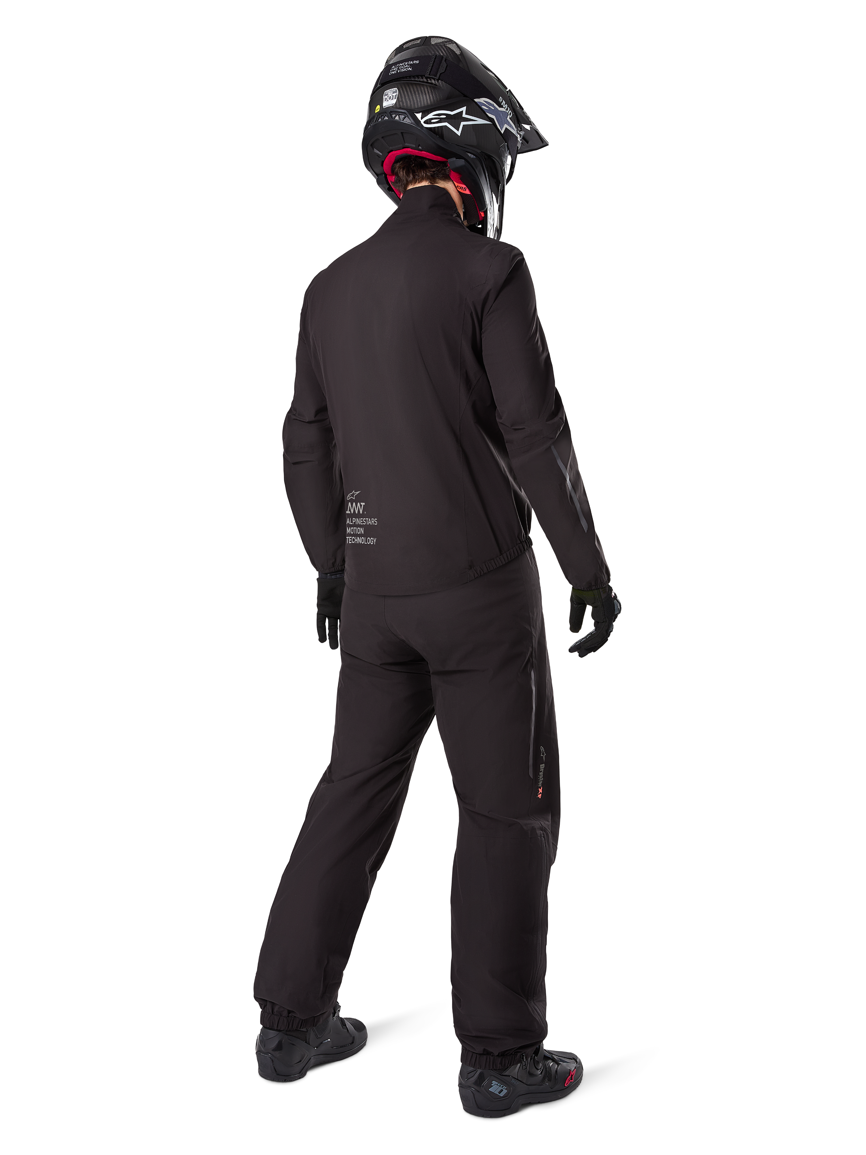 Motorcycle rider seen from behind wearing the black Amt-8 Stretch Drystar® XF Pants and matching jacket, complete adventure touring outfit with black helmet and boots, technical waterproof and stretchable gear for long-range motorcycling