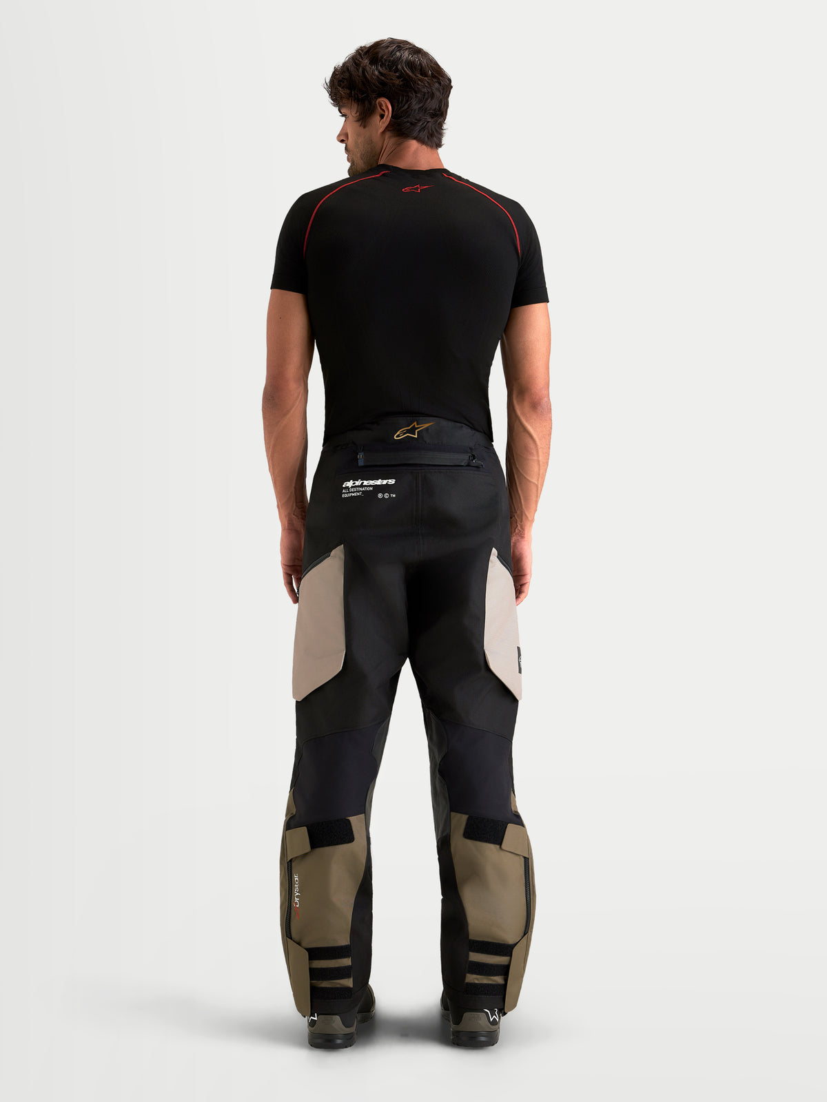 Alpinestars Harok V2 Drystar, pantalones de moto de aventura para hombre, aluminio, marrón y negro, vista trasera en modelo que muestra la construcción de ripstop duradera y el diseño over-the-boot