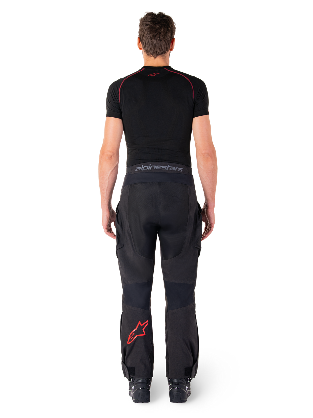 Alpinestars Hyde Xt Drystar® Pants, Adventure Touring Motorcycle Pants, Black and Bright Red, rear view of a rider wearing the pants and a black base layer, featuring a red star logo on the left leg and grey branding on the waistband.