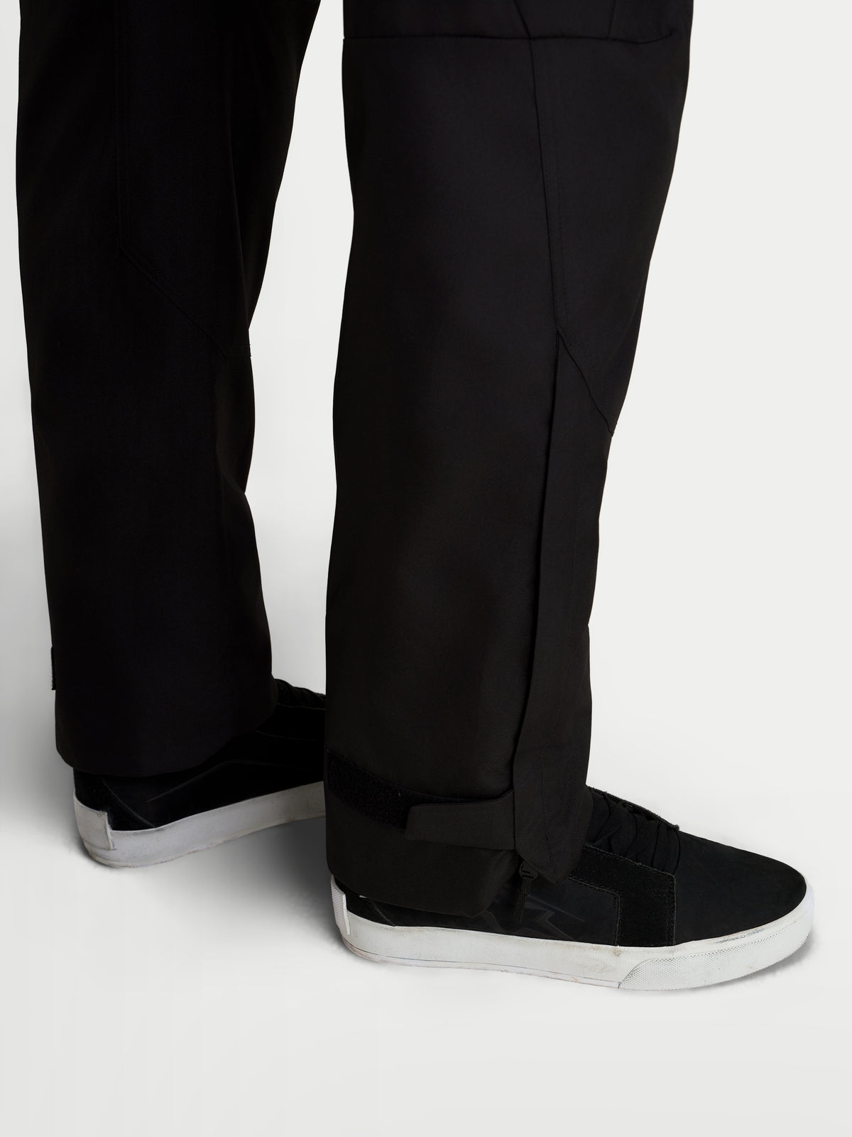 Alpinestars C-1 Waterproof Pantalones, pantalones de moto urbanos contemporáneos para hombre, de color negro, vista en primer plano de la construcción de la parte inferior de la pierna con corte recto y aberturas de pierna extendidas usadas con zapatos de moto