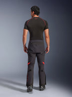 Pantalones laminados Alpinestars Halo Pro Drystar® XF, pantalones de moto de aventura, color Black Dark Shadow con detalles en rojo, vista trasera, usados con una capa base negra de manga corta y botas de aventura negras, destacando su construcción laminada duradera de 3 capas y ajuste ergonómico.