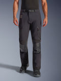 Alpinestars Halo Pro Drystar® XF Laminated Pants en Black Dark Shadow, pantalones de moto de aventura, vista frontal en el modelo con hebilla magnética en la cintura, ventilaciones con cremallera en los muslos y parches de cuero reforzados en las rodillas, combinados con botas de moto negras.