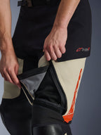 Alpinestars Halo Pro Drystar® XF Laminated Pants, Mastic Black, detalle en primer plano de la ventilación con cremallera en el muslo abierta para mostrar el panel de malla interno para el flujo de aire, con el logotipo Drystar XF en rojo y detalles gráficos en naranja
