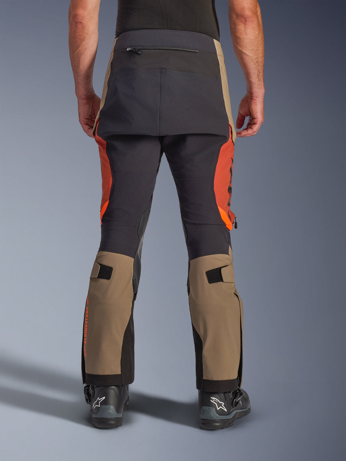 Pantalones laminados Alpinestars Halo Pro Drystar® XF en Walnut Rust Black, vista trasera, pantalones de moto de aventura con paneles en color nogal y naranja óxido, refuerzo negro en el asiento, bolsillo trasero con cremallera y correas de ajuste en la pantorrilla