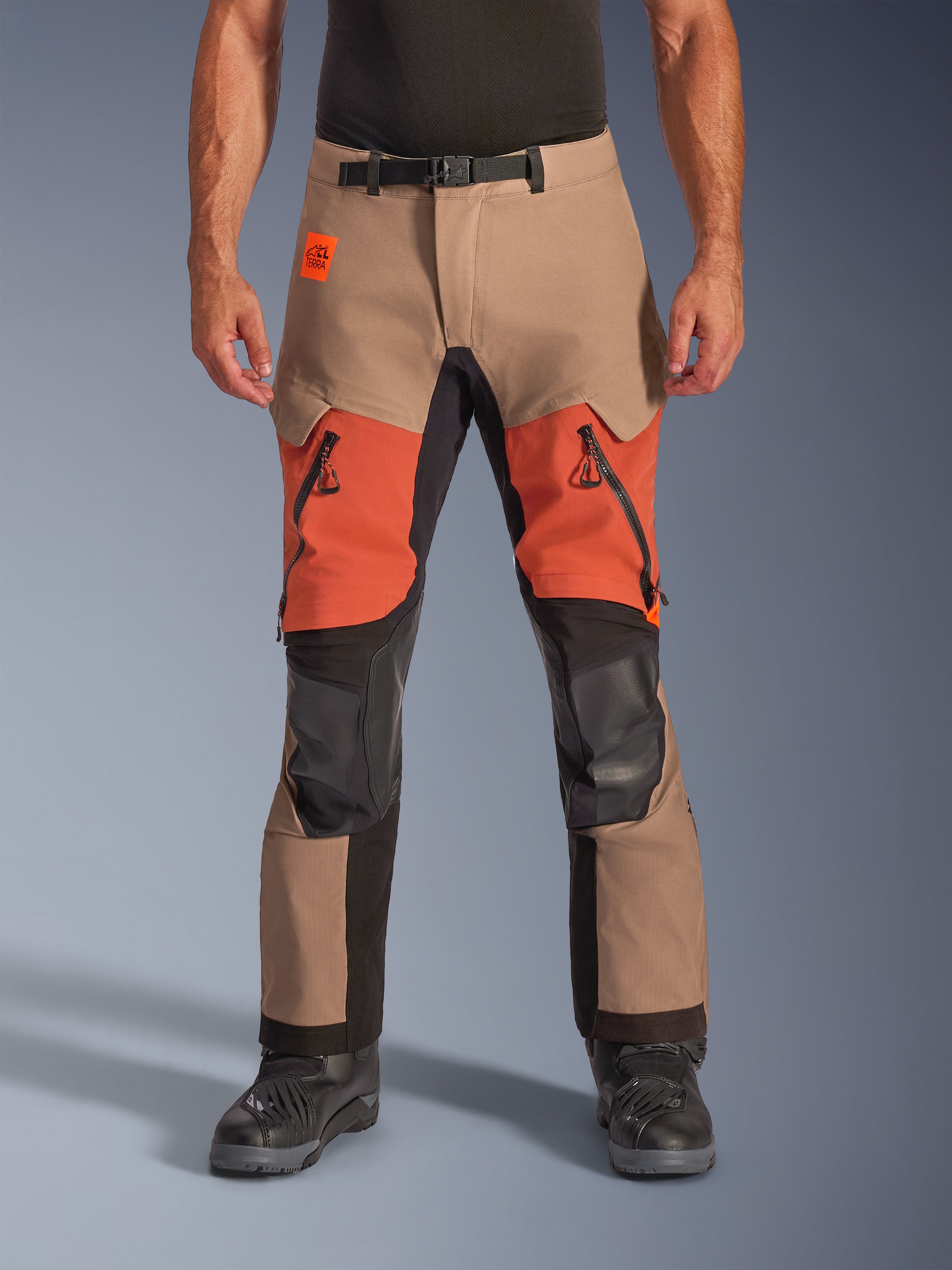 Pantalones Alpinestars Halo Pro Drystar XF Laminated, pantalones de motociclismo de aventura y turismo, colores nuez, óxido y negro, con construcción laminada impermeable, vista frontal con ventilaciones naranjas en los muslos, cremalleras negras YKK AQUASEAL y cinturón ajustable.