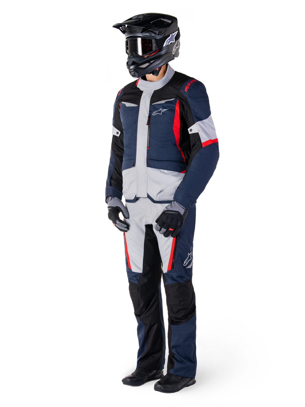 Pantalones Alpinestars St-1 Waterproof, pantalones de turismo de aventura, azul oscuro, negro y rojo brillante, usados con una chaqueta de turismo a juego, casco, guantes y botas negros, con paneles gris claro, detalles en rojo y logotipos de Alpinestars, diseñados para la conducción en cualquier condición climática.