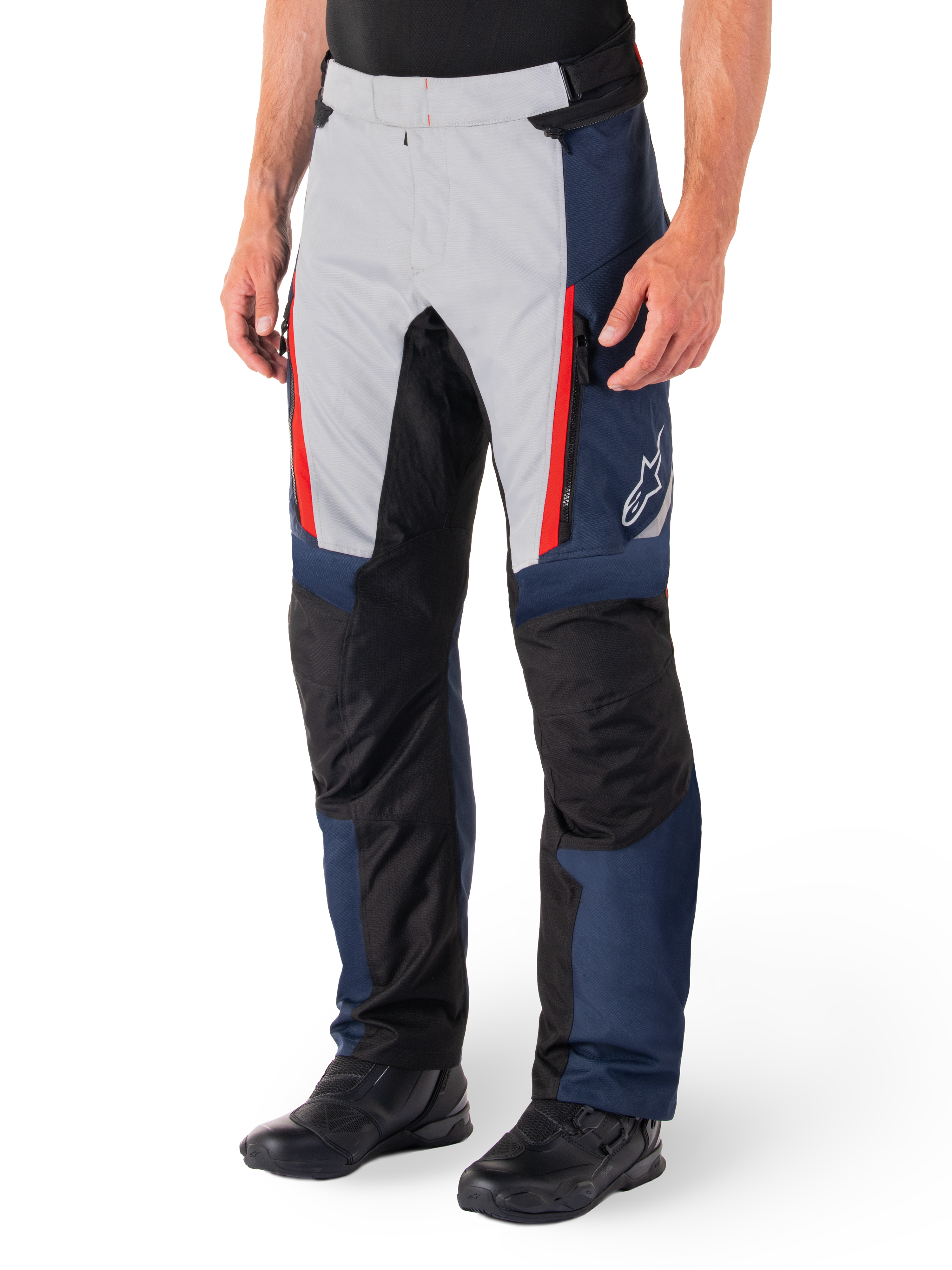 Pantalones Alpinestars St-1 Waterproof, pantalones de touring para moto, azul oscuro, negro y rojo brillante, con paneles frontales gris claro, acentos de cremalleras rojas, secciones de rodilla reforzadas en negro y logo blanco de Alpinestars en el lateral, usados con botas de moto negras