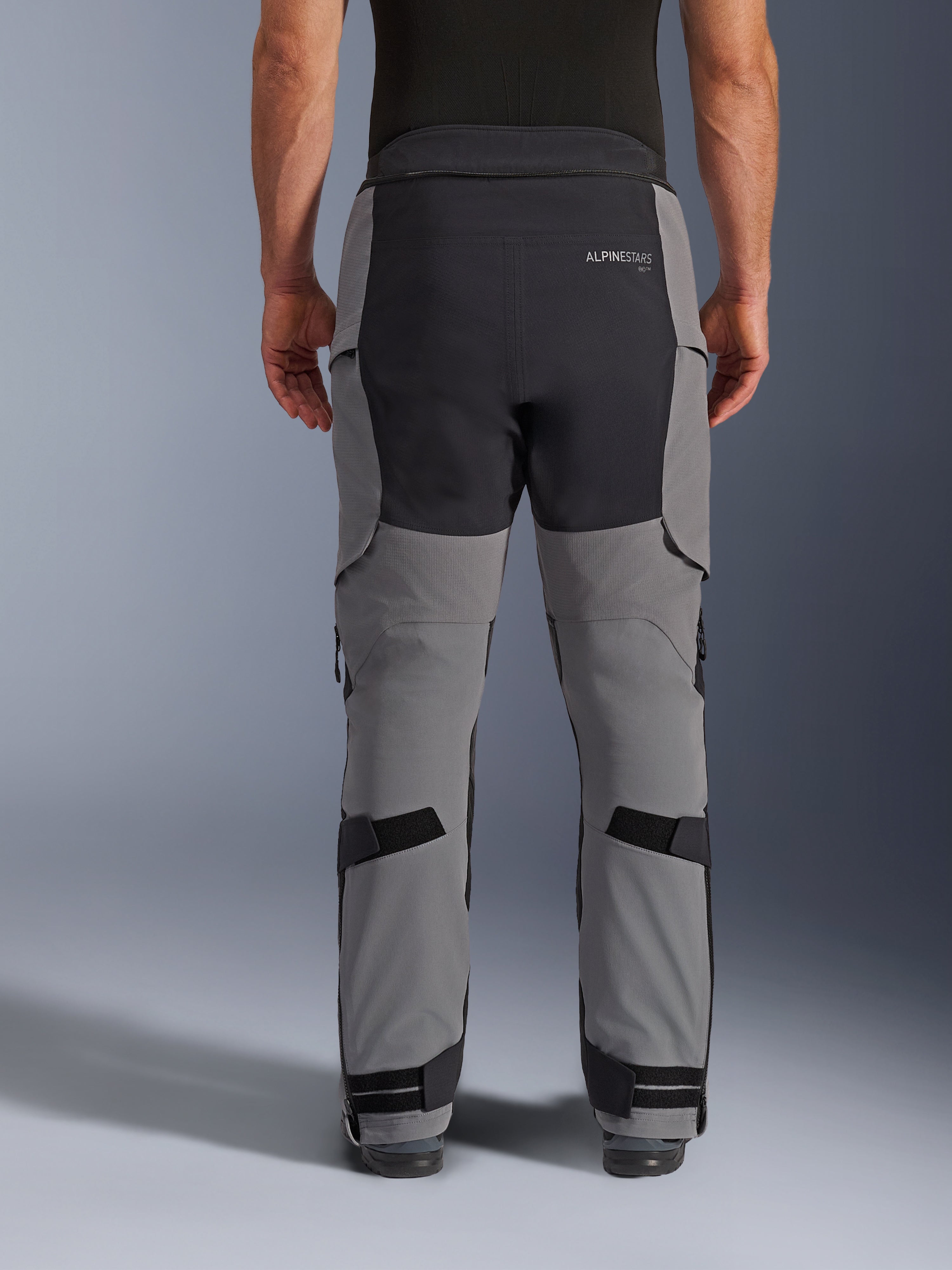Pantalones Alpinestars Andes Pro Drystar® XF, vista trasera, gris oscuro y negro, pantalones de motociclismo de aventura con paneles reforzados negros en el asiento, logotipo trasero de Alpinestars y correas ajustables detrás de las rodillas y en los tobillos para un ajuste seguro.