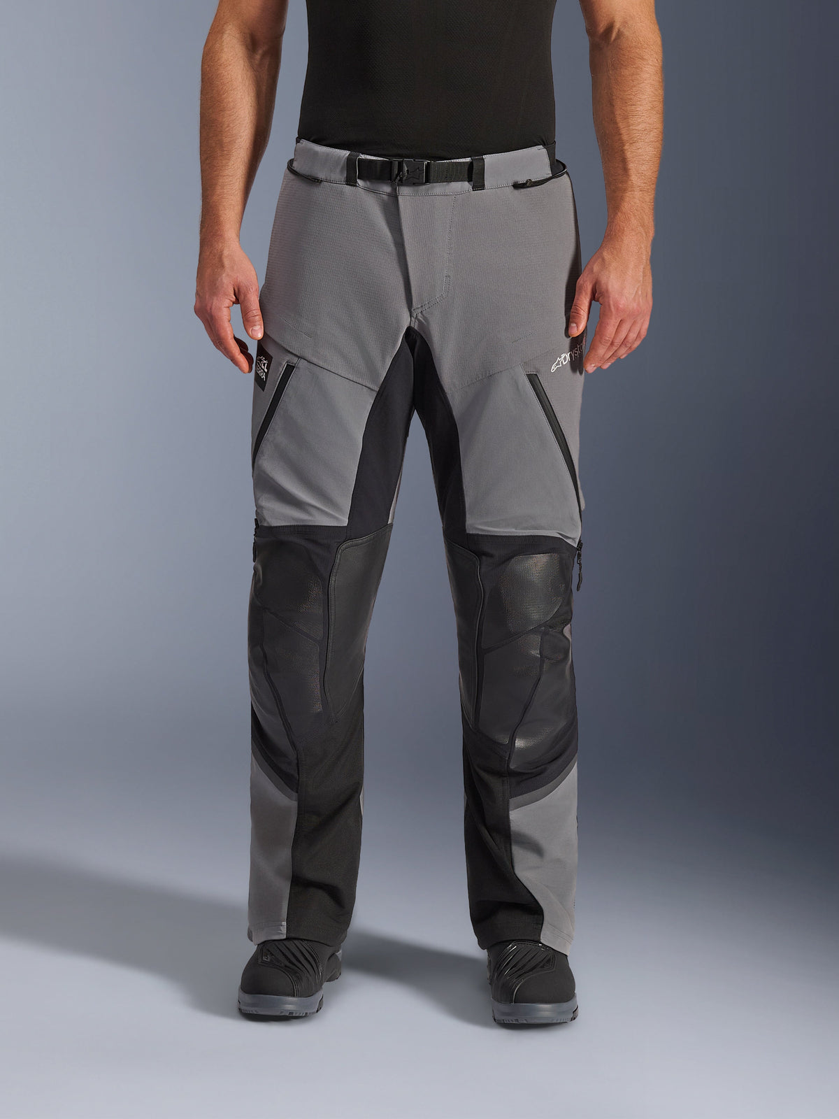 Alpinestars Andes Pro Drystar® XF Pants, Motorcycle Pants, Dark Gray and Black, front view, featuring reinforced black knee panels, waterproof zippers, and magnetic buckle belt, worn with black boots