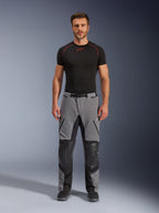 Pantalones Alpinestars Andes Pro Drystar® XF, pantalones de motociclismo de aventura, gris oscuro y negro, vista frontal usados por un modelo con una capa base negra, con paneles reforzados en las rodillas y bolsillos impermeables con cremallera