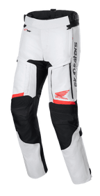 Pantalones Honda Bogota' Pro Drystar®, pantalones de moto touring, gris hielo y negro con acentos rojos, vista frontal que muestra paneles de ventilación en los muslos y rodillas en acordeón, logos rojos del ala de Honda y Alpinestars, equipo técnico impermeable para aventura