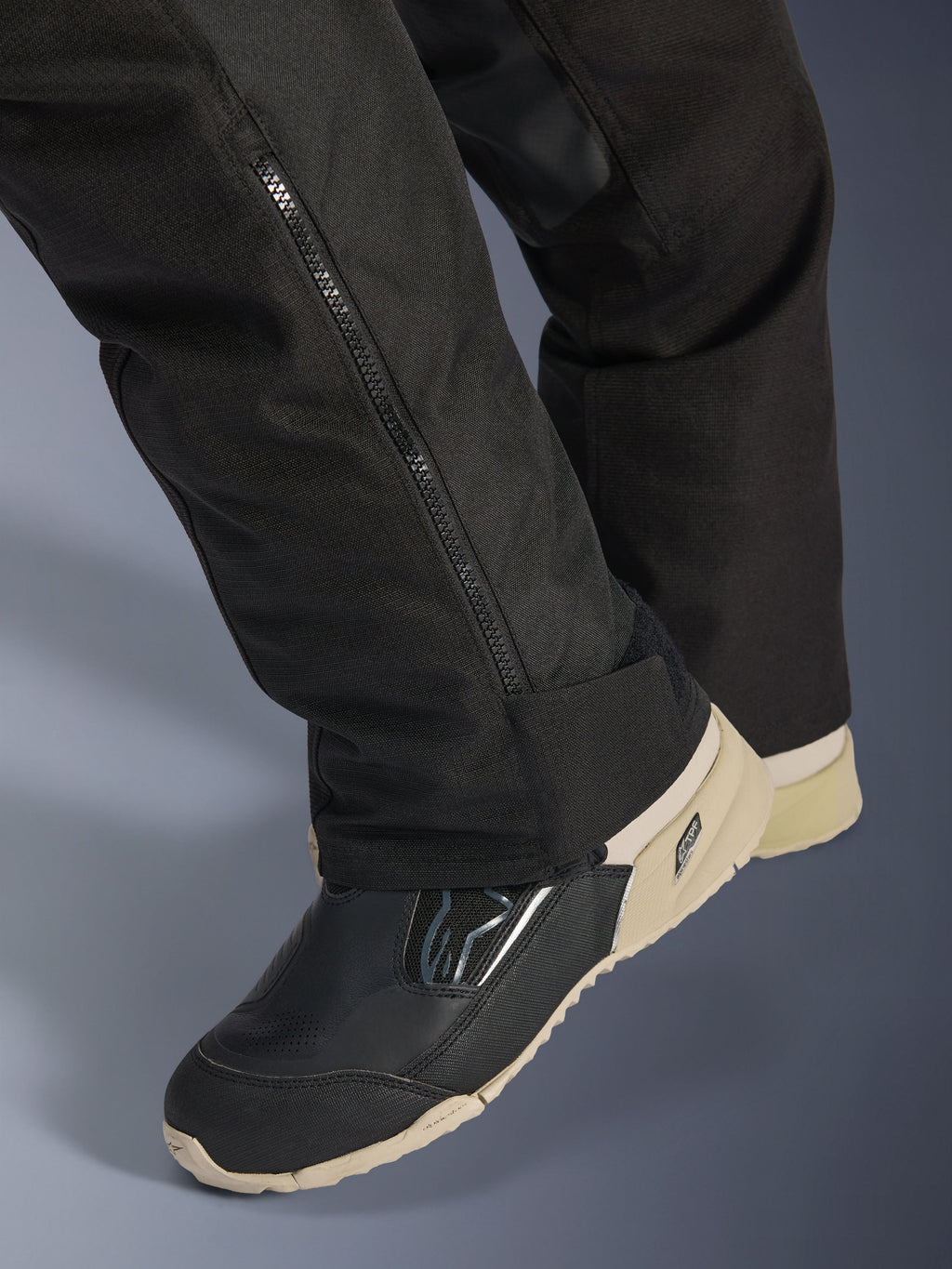 Alpinestars Stella Andes V4 Drystar® Pants, Black, close-up of lower leg featuring a side zipper for boot adjustment, durable textile material, worn with black and tan motorcycle boots, adventure-ready functional design