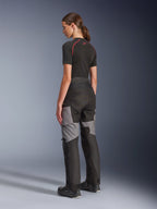 Pantalones Stella Andes V4 Drystar® para mujer, pantalones de moto para aventura y turismo en negro y gris oscuro, vista trasera y lateral en modelo, con construcción textil duradera con paneles de refuerzo grises y un ajuste entallado para motociclistas