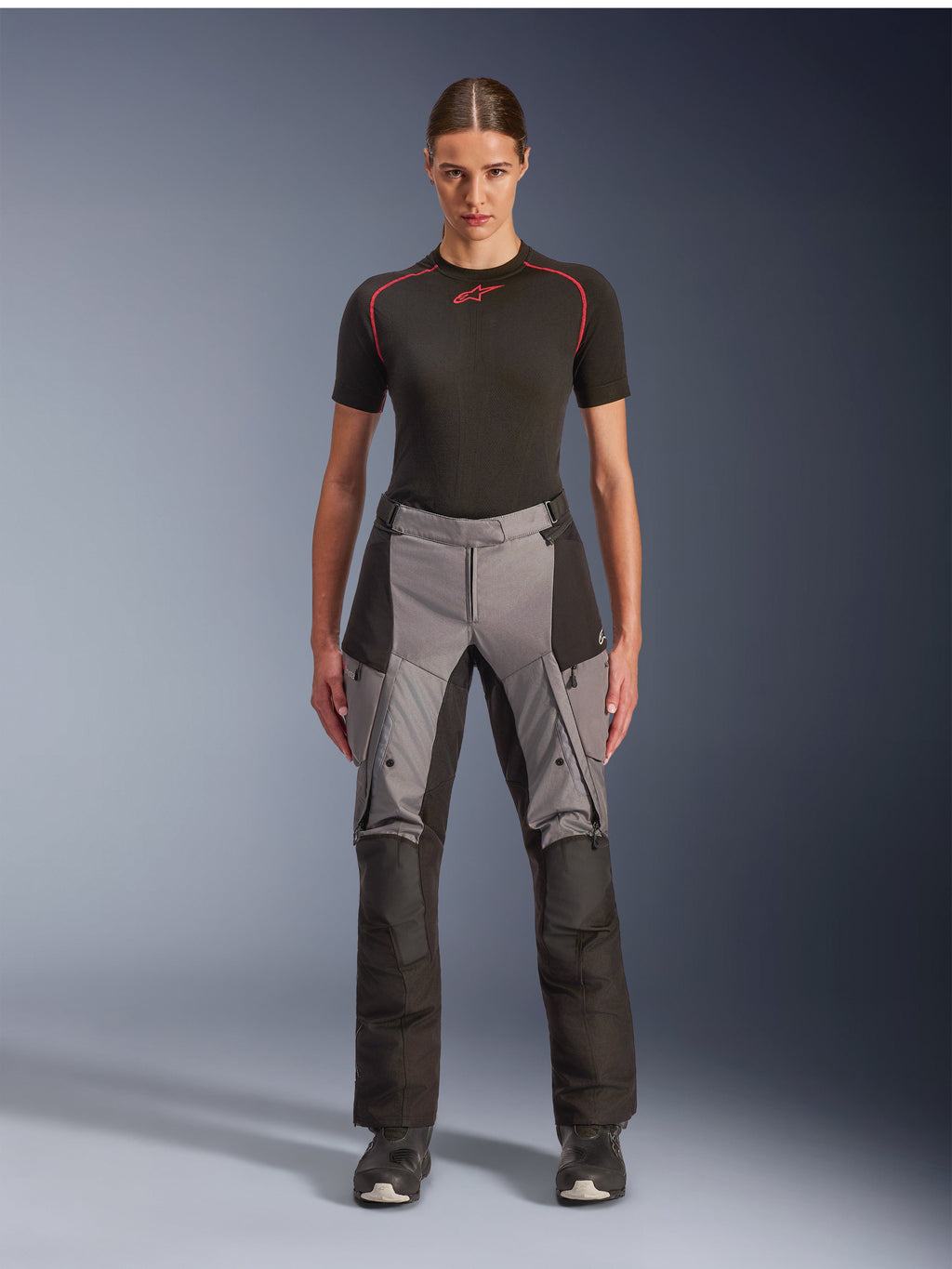 Pantalones Alpinestars Stella Andes V4 Drystar, pantalones de moto adventure touring para mujer, negro y gris oscuro, usados por una modelo con una capa base negra y botas de moto, con paneles textiles reforzados y bolsillos de carga para conducción de aventura