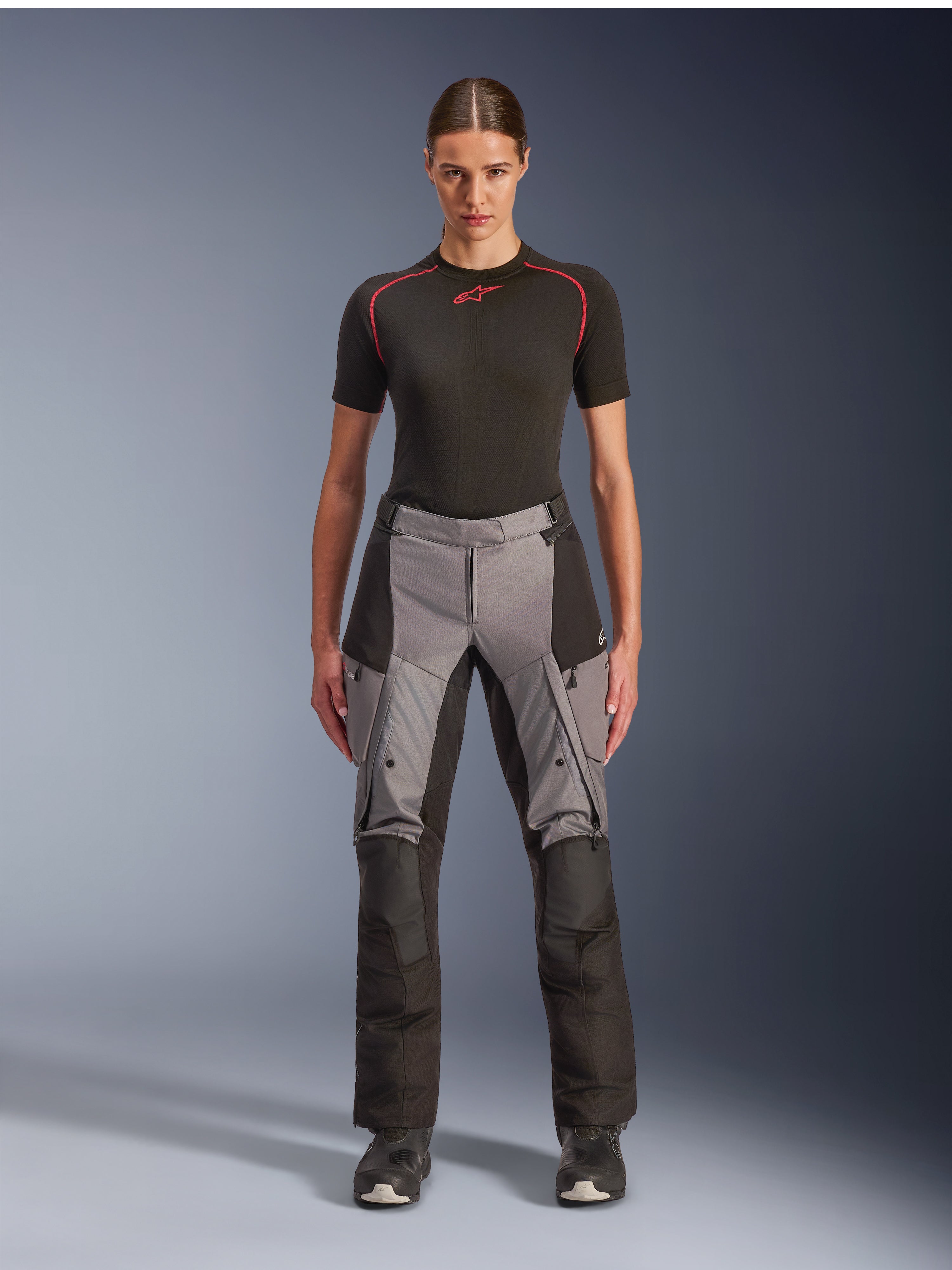 Pantalones Alpinestars Stella Andes V4 Drystar, pantalones de moto adventure touring para mujer, negro y gris oscuro, usados por una modelo con una capa base negra y botas de moto, con paneles textiles reforzados y bolsillos de carga para conducción de aventura