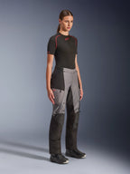 Pantalones Alpinestars Stella Andes V4 Drystar®, pantalones de moto de aventura para mujer, negro y gris oscuro, lucidos por una modelo con una capa base Alpinestars negra y botas negras, con paneles reforzados, logotipo Drystar rojo y bolsillos cargo.