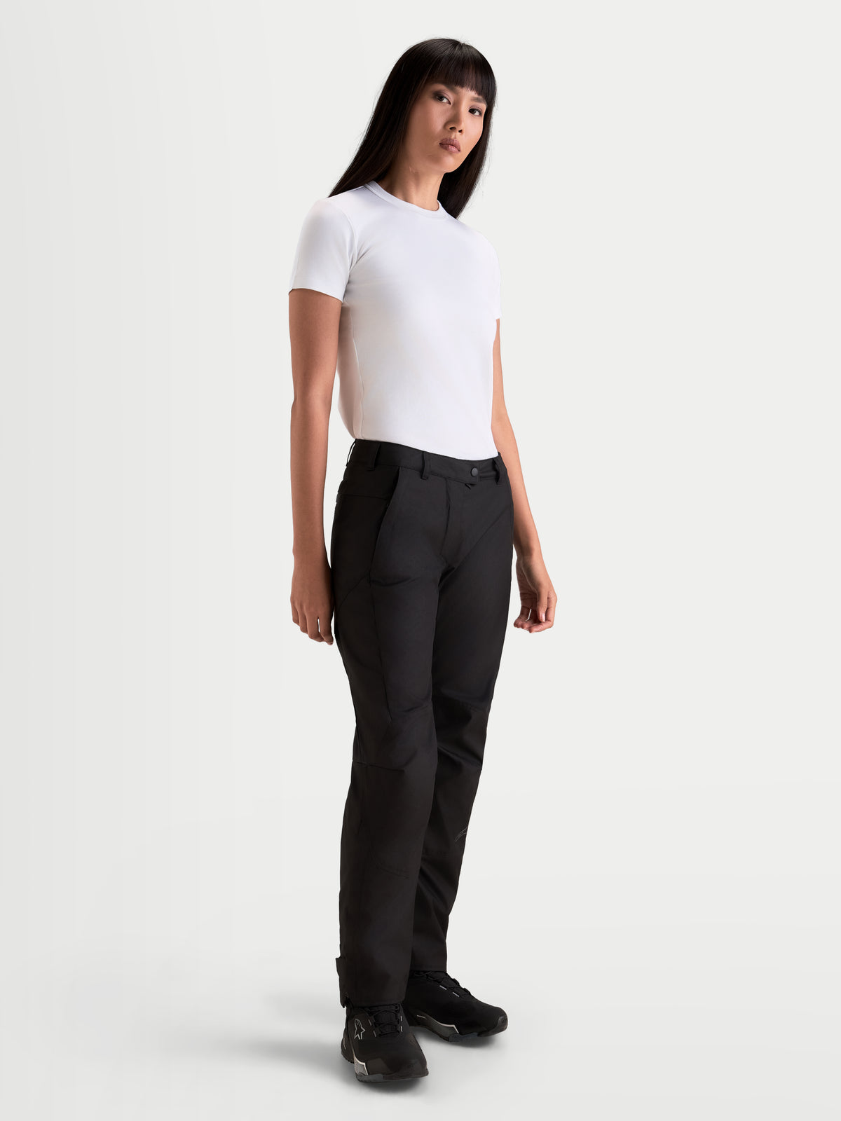 Alpinestars Stella C 1 Waterproof Pantalones, pantalones de moto urbanos para mujer, negros, de construcción textil con pernera recta, con una camiseta blanca en modelo, ropa de equitación para clima frío