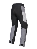 Alpinestars 2025 Honda Stella ST-1 Waterproof Pants para mujer, pantalones de motociclismo touring para mujer, gris hielo, gris oscuro y negro, vista trasera en tres cuartos que muestra la construcción textil duradera, paneles de bloques de color gris y negro, marca Honda en la cadera y cierres ajustables en los tobillos.