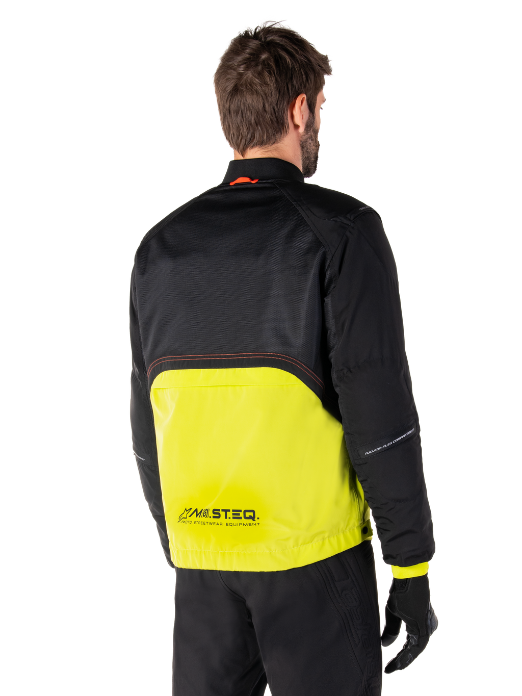 Alpinestars Mootant Waterproof Parka, chaqueta de moto, Lime Punch y negro, vista trasera que muestra la malla superior negra y la sección inferior verde lima brillante, con la marca MO.ST.EQ., usada con pantalones de conducción y guantes negros