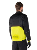 Alpinestars Mootant Waterproof Parka, chaqueta de moto, Lime Punch y negro, vista trasera que muestra la malla superior negra y la sección inferior verde lima brillante, con la marca MO.ST.EQ., usada con pantalones de conducción y guantes negros