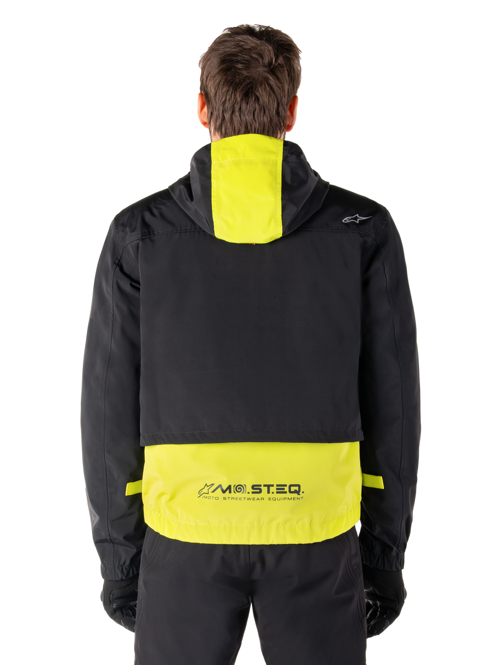 Parka impermeable Alpinestars Mootant, chaqueta de moto, en Lime Punch y negro, vista trasera que muestra el diseño con capucha y la marca reflectante MO.ST.EQ. en la parte inferior de la espalda, combinada con pantalones y guantes de moto negros.