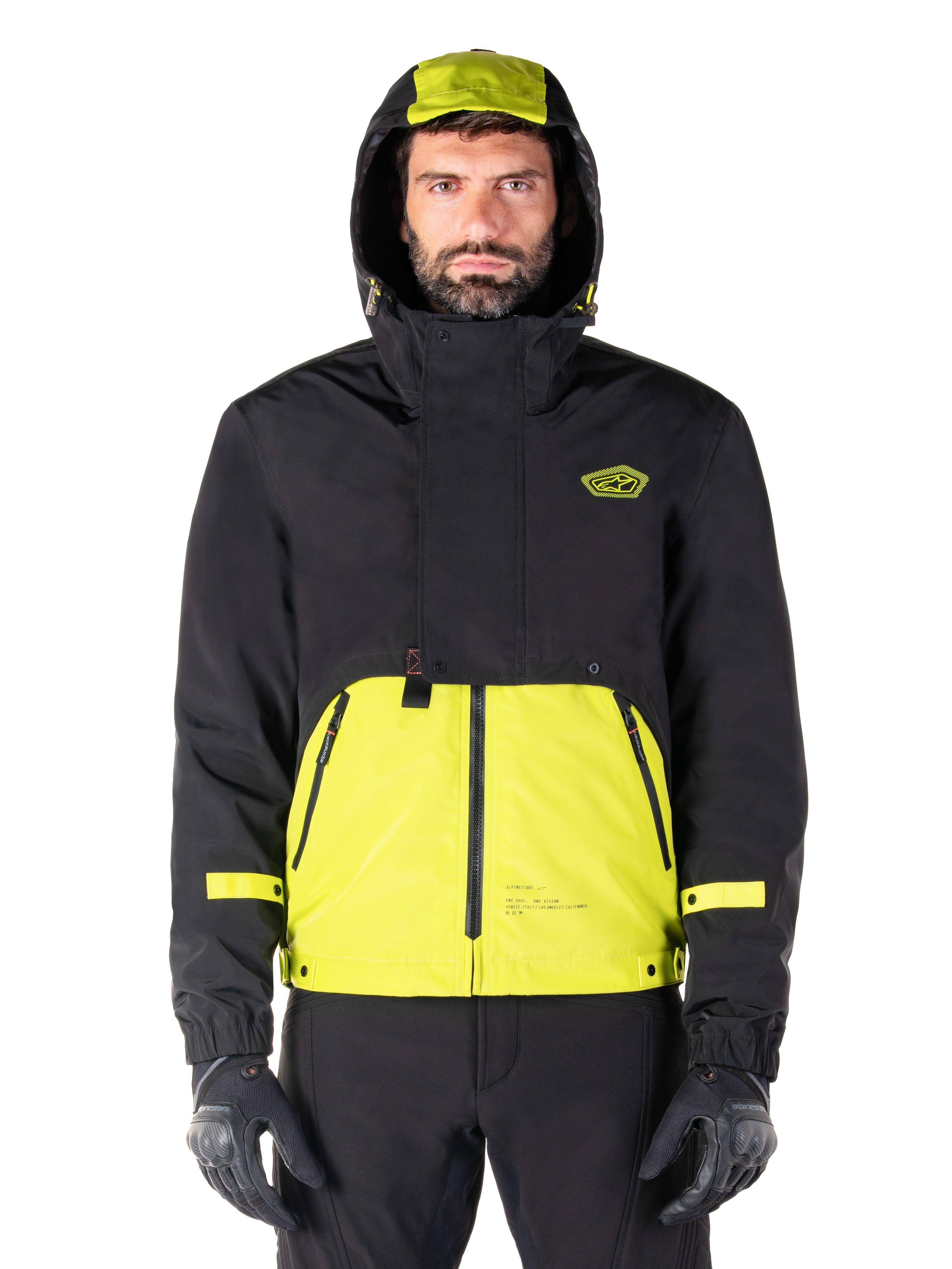 Parka impermeable Alpinestars Mootant, chaqueta de moto en color Lime Punch Black, vista frontal, diseño modular 3 en 1 con parte superior negra y sección inferior en verde lima brillante, con capucha con cordón y logotipo en el pecho, combinada con pantalones negros y guantes de moto