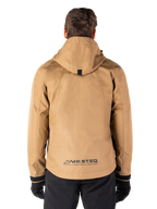 Parka impermeable Alpinestars Morush, color marrón Utility Brown, vista trasera, con capucha y logotipo MO.ST.EQ. en la parte inferior de la espalda, combinada con pantalones y guantes negros, equipamiento de motociclismo de estilo urbano moderno
