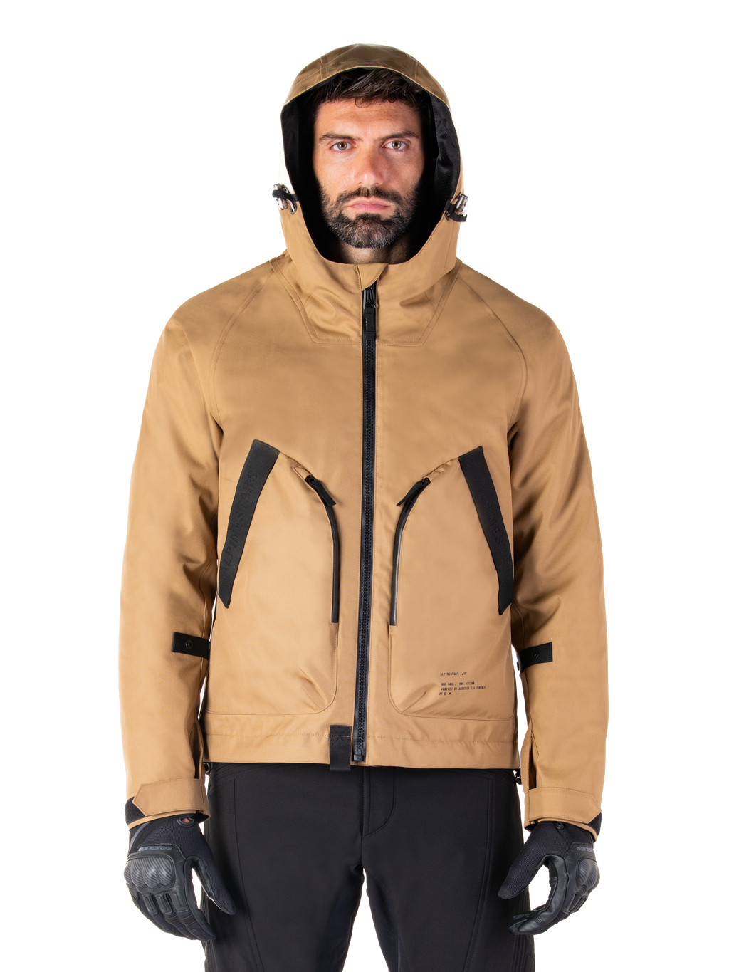 Parka impermeable Alpinestars Morush, chaqueta de moto, marrón utility, diseño con capucha inspirado en el estilo urbano con grandes bolsillos delanteros con detalles en negro, usada con guantes y pantalones de moto negros, equipamiento de moto urbano contemporáneo
