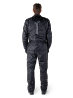 Mono Hurricane Rain V2 de Alpinestars, traje de moto impermeable de una pieza en color negro, vista trasera que muestra el logotipo y la marca denominativa vertical de Alpinestars en grande, tejido ligero arrugado con cintura y puños elásticos, diseñado para la protección al conducir bajo la lluvia.