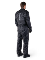 Alpinestars Hurricane Rain V2 Suit, mono de lluvia impermeable para motocicleta de una pieza en color negro, vista trasera con gran logotipo reflectante vertical, tejido ligero resistente al viento, usado con guantes y botas negras