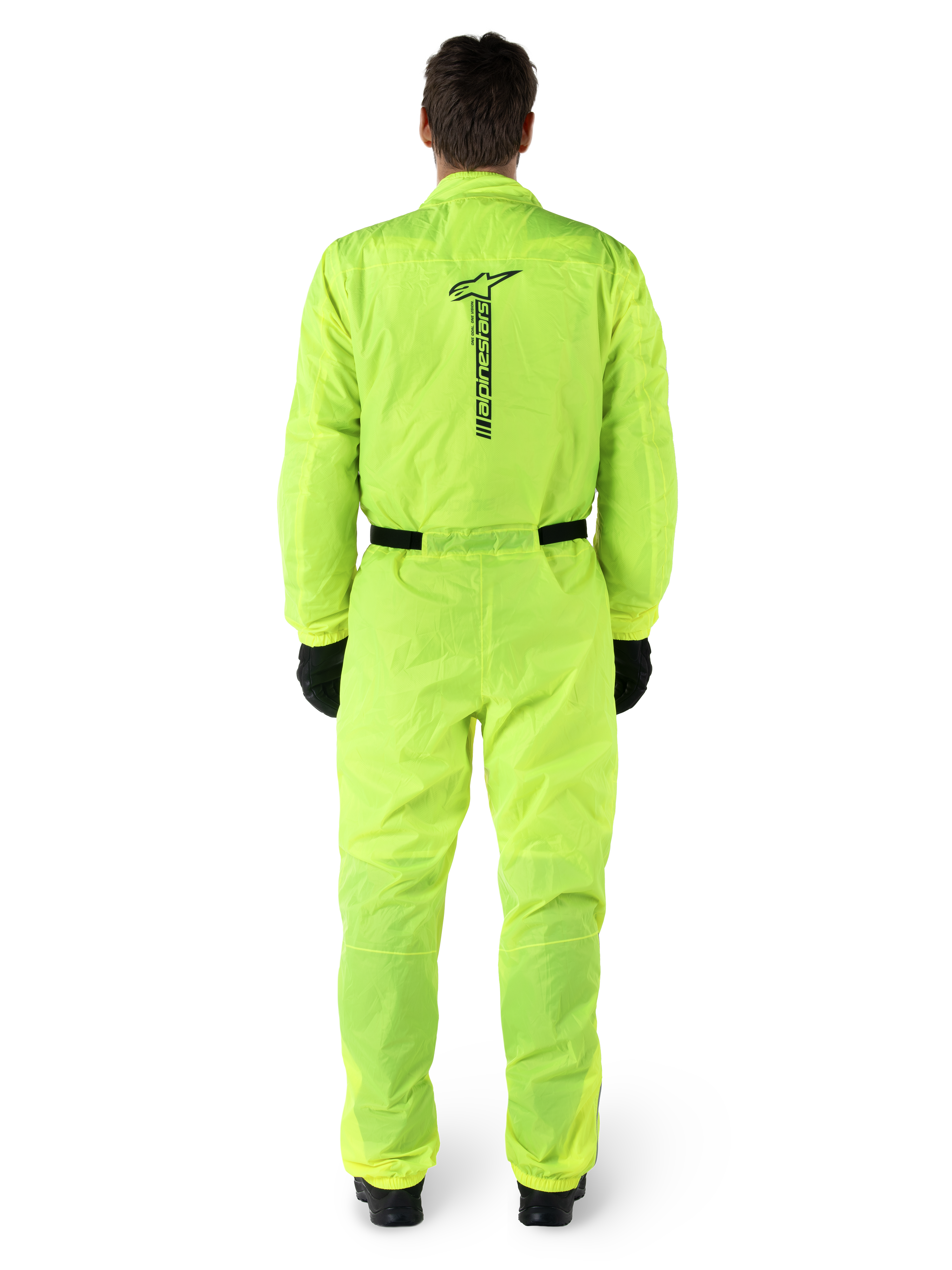 Mono Alpinestars Hurricane Rain V2, traje de lluvia de una pieza para moto, amarillo flúor, vista posterior con marca Alpinestars vertical en negro, cintura y puños elásticos, usado con guantes y botas negras, equipamiento impermeable y resistente al viento