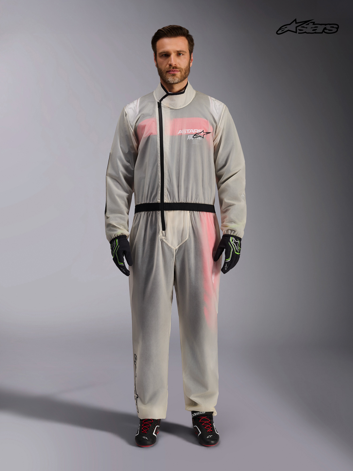Alpinestars Traje De Lluvia De Karting, traje impermeable transparente de karting para hombre en color claro, vista frontal en modelo mostrando la cremallera asimétrica y la cintura elástica